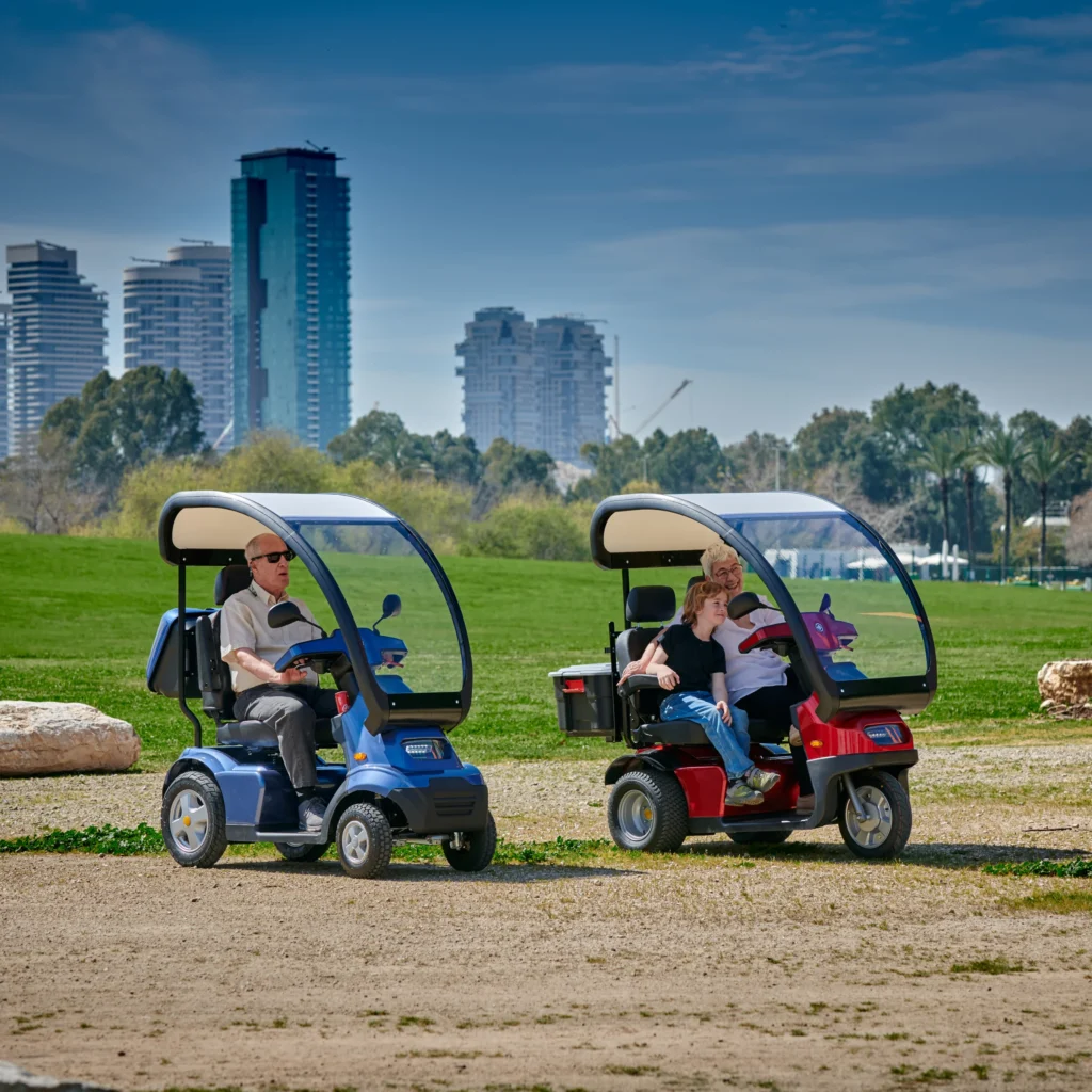 Lifestyle Image Side View of Blue Afiscooter S4 with Canopy Mobility Scooter, Red Afiscooter S3 Dual Seat Mobility Scooter with Canopy Golf Tires