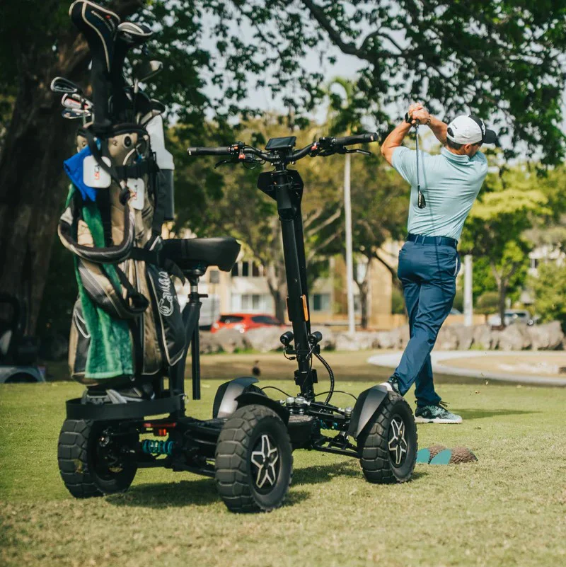 Outdoor view of the MIA Four X2 scooter on a golf course with a golfer swinging in the background