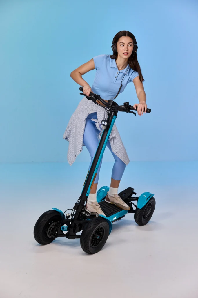 A Women standing on MIA SPYQE 2x4 electric scooter with strong suspension and wide tires designed for smooth and powerful urban riding shop the SPYQE now