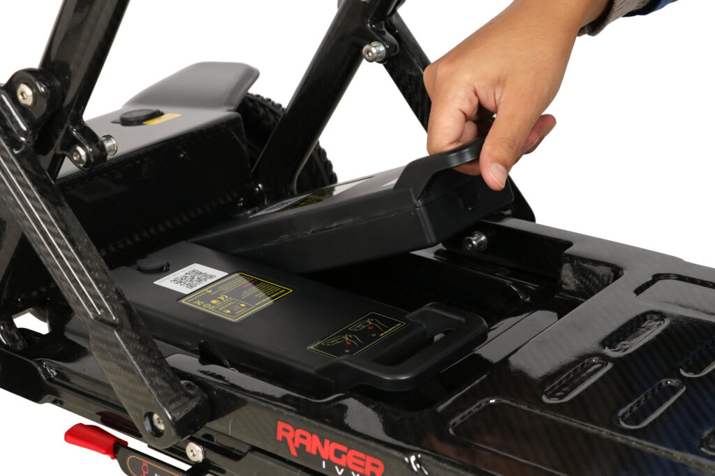 Porto Mobility Ranger Ivy folding scooter, hand lifting a battery pack out of the deck