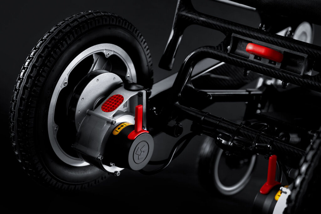 Porto Mobility Ranger SpacePro folding power wheelchair, rear wheel hub with red lever close up